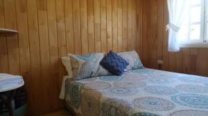 - une chambre avec un lit doté de murs en bois et d'une fenêtre dans l'établissement Cabañas Sotobosque, à Puelo