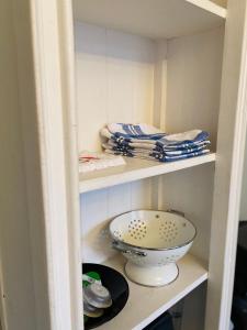 un armario con un tazón, platos y toallas en Lily-Rose Cottage, en Vastorf