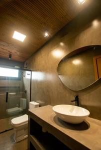 y baño con lavabo, aseo y espejo. en Casa moderna prox ao centro na Praia do Rosa SC, en Imbituba