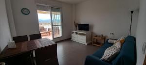 ein Wohnzimmer mit einem blauen Sofa und einem Tisch in der Unterkunft Apartamento Cerezo Beach in Xilxes