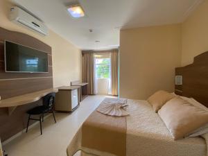 um quarto com uma cama, uma secretária e uma televisão em Kanoa Hotel em Santo Antônio da Platina