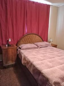 1 dormitorio con cama y cortina roja en La nona - Departamento en Godoy Cruz