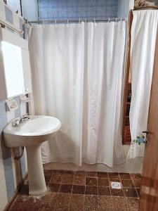 baño con cortina de ducha blanca y lavamanos en La nona - Departamento en Godoy Cruz