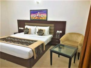 - une chambre avec un lit, une chaise et une table dans l'établissement Tavisha Villa Flim City Road Dadri Road, à Noida
