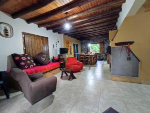 sala de estar con sofá rojo y mesa en Casa de campo de piedra en Tunuyán
