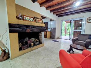 uma sala de estar com lareira e uma cadeira vermelha em Casa de campo de piedra em Tunuyán