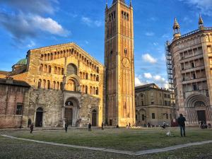 una torre del reloj alta frente a un edificio en Opera 11 r&b en Parma