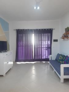 a living room with a purple curtain and a couch at A.M.A Appartament in Calheta Do Maio