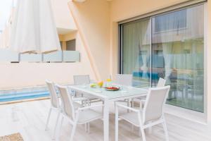 a white dining room with a white table and chairs at Modern villa with pool jacuzzi and sea view in La Horadada