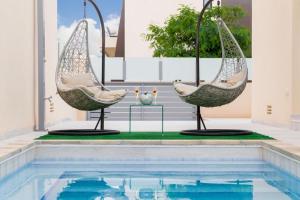 a pool with two swinging chairs next to a swimming pool at Modern villa with pool jacuzzi and sea view in La Horadada +14 photos