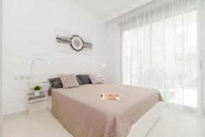 a white bedroom with a bed and a large window at Modern villa with pool jacuzzi and sea view in La Horadada