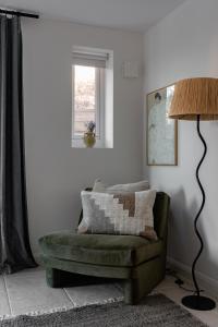 a living room with a green couch and a lamp at Luxury Eton Cottage-Design Led in Eton