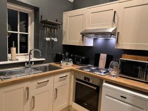a kitchen with white cabinets and a sink at Stonehenge Cottages in Salisbury