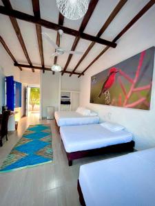 ein Schlafzimmer mit 3 Betten und einem roten Vogel an der Wand in der Unterkunft Hotel Parque la Casona in Garzón