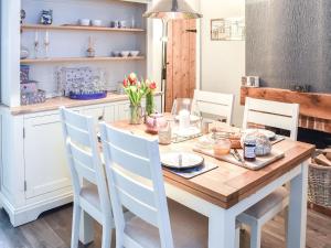 a kitchen with a wooden table with white chairs at Fuchsia Cottage in Sea Palling
