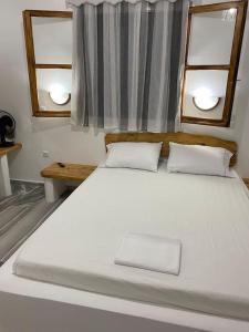 1 cama blanca grande en una habitación con 2 ventanas en George's Home Platy Gyalos, en Kalymnos