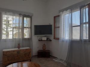 a living room with a tv and two windows at George's Home Platy Gyalos in Kalymnos