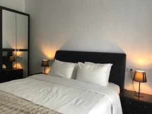 a bedroom with a bed with white sheets and two lamps at Comfortable Apartment in Cartier Evocasa Orizont Ploiesti (North) in Ploieşti