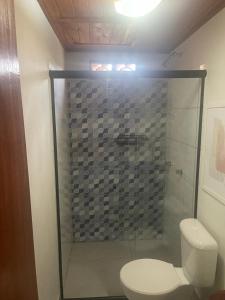 a bathroom with a glass shower with a toilet at Pousada Meraki Paraty Mirim in Paraty