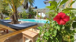 a patio with a bench and a red flower and a pool at Nakupenda paje villa in Paje