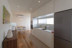una cocina con armarios blancos y una mesa. en Sea & Rocks 15 - House en Lagoa