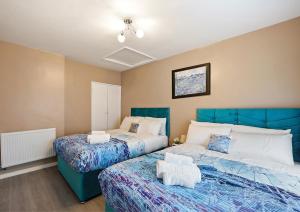 Duas camas num quarto com azul e branco em Three Bed Luxury Home in London em Abbey Wood