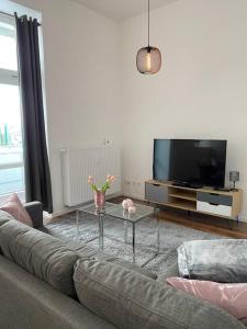 - un salon avec un canapé et une table basse en verre dans l'établissement AKK3 Apartment Magdeburg Altstadt Zentral Balkon, à Magdebourg