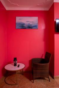 a room with a red wall with a table and chairs at Karay Apartments in Wakiso