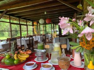 einen Tisch mit Essen und Blumen auf einem roten Tischtuch in der Unterkunft Pousada Cabanas da Serra Lumiar in Lumiar
