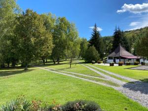 un campo de césped con cenador y árboles en Forrás camping, en Magyarhertelend