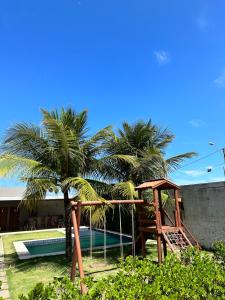 een speeltuin naast een palmboom en een zwembad bij Casa New York in Aquiraz