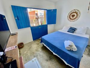 1 dormitorio con puertas azules y 1 cama con toallas en Pousada Le Petit Suítes ER Hospedagens, en Porto de Pedras