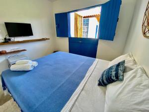 1 dormitorio con cama con sábanas azules y ventana en Pousada Le Petit Suítes ER Hospedagens, en Porto de Pedras