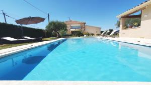 a large blue swimming pool with an umbrella at L'OUSTAL D'ADELE proche Canal du Midi et Moissac in Saint-Nicolas-de-la-Grave