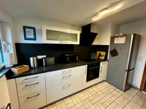  La cuisine est équipée de placards blancs et d'un réfrigérateur. dans l'établissement OhPardon! GAILDORF - DG Wohnung, Garten, Smart-TV, à Gaildorf