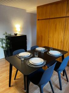 a black table with chairs and plates on it at OhPardon! GAILDORF - DG Wohnung, Garten, Smart-TV in Gaildorf