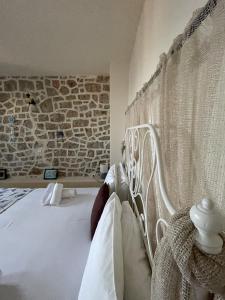 Cama blanca en habitación con pared de piedra en Marina Castellana Studios II en Halki