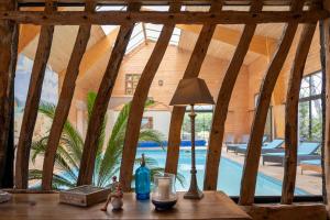 a table with a lamp on a table in a room with a pool at Nature et Lin in Néville