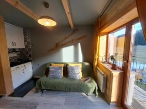 Habitación pequeña con sofá verde y ventana en Noclegi przy Lesie, en Zakopane