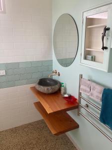 ein Badezimmer mit einem Steinwaschbecken und einem Spiegel in der Unterkunft Commanding Harbour views exquisite sunset vista in Dunedin