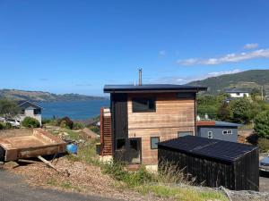 uma pequena casa com um terraço ao lado de uma estrada em Commanding Harbour views exquisite sunset vista em Dunedin