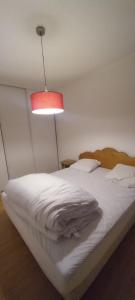 1 dormitorio con cama blanca y lámpara roja en Le gîte du Val, en Flumet