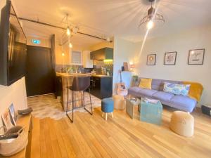 ein Wohnzimmer mit einem blauen Sofa und einer Küche in der Unterkunft La Pause de Mérimée - T2 - Parking - Jardin in Vannes