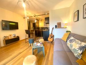 sala de estar con sofá y guitarra en La Pause de Mérimée - T2 - Parking - Jardin en Vannes