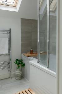 a bathroom with a glass shower with a potted plant at Luxury Eton Cottage-Design Led in Eton +44 photos