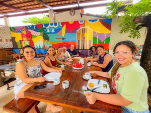 a group of people sitting around a wooden table at Villa Flecheiras in Flecheiras