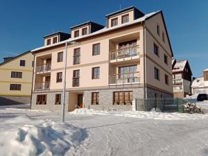 a large building with snow in front of it at Apartman Hubert in Kašperské Hory
