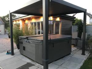 a hot tub under a cover on a patio at Amazing Cottage & detached Annex sleeps 8, Extra Deep Hot tub, Super Fast wifi, New for 2024 is the addition of Wood Fired Sauna in Castle Douglas