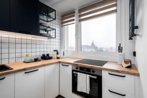 a kitchen with white cabinets and a large window at Kairos Apartments - Gold - darmowy Parking, ścisłe centrum in Gliwice