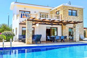 een villa met een zwembad en een huis bij Villa Olivia Coral in Peyia